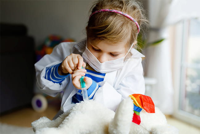 Child plays doctor with stuffed animal