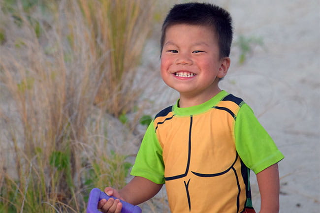 Image of child on sandy dunes smiling