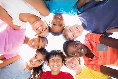 Children together in a circle looking down.