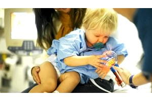image of child in the lap of a caregiver playing with a toy