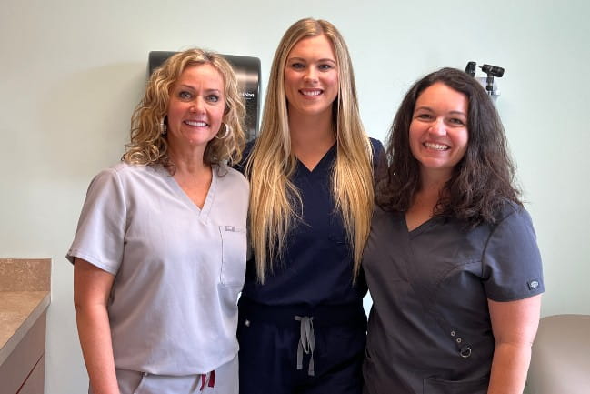 MUSC Children's Health Concussion Clinic Care Team Members Kikki Thayer, MS, CCC-SLP, Savannah Wawner, PA, MPAS and Stacey Gray, PT, DPT, PCS smile in clinic.