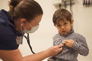 A screenshot of the MUSC Pediatric Primary Care video of a nurse checking a child with a stethescope.
