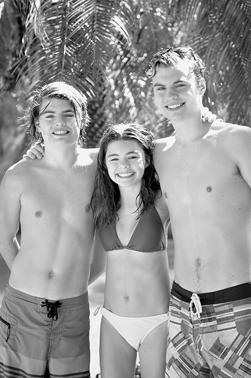 Three teens stand in swimsuits