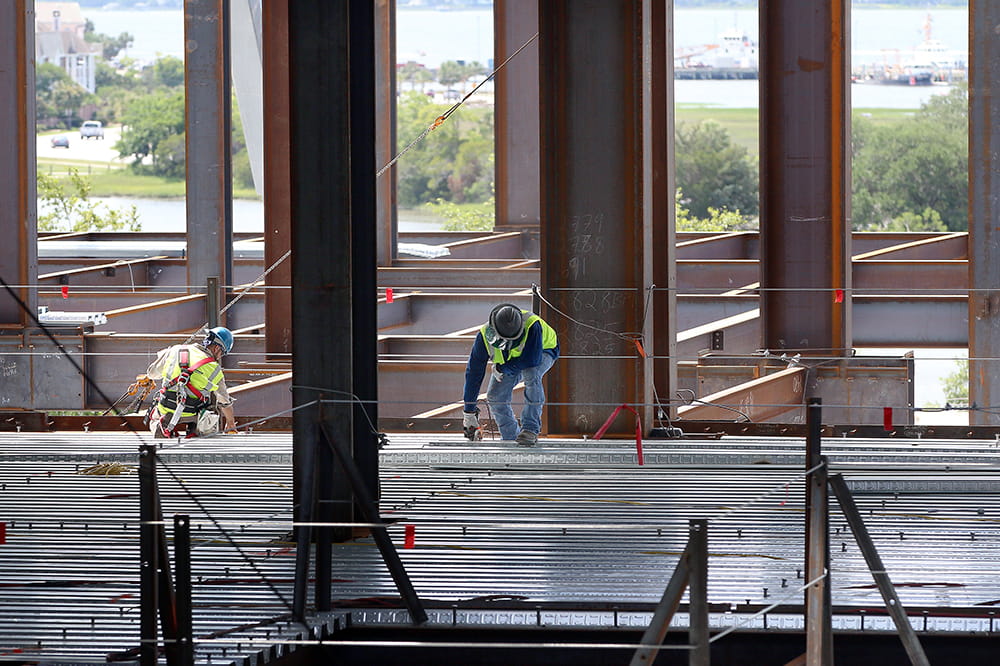 two workers surrounded by open girders work on the children's hospital