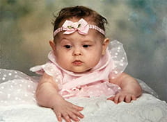 Photo of a baby girl propped surrounded by  pink tulle dress with puffy sleeves