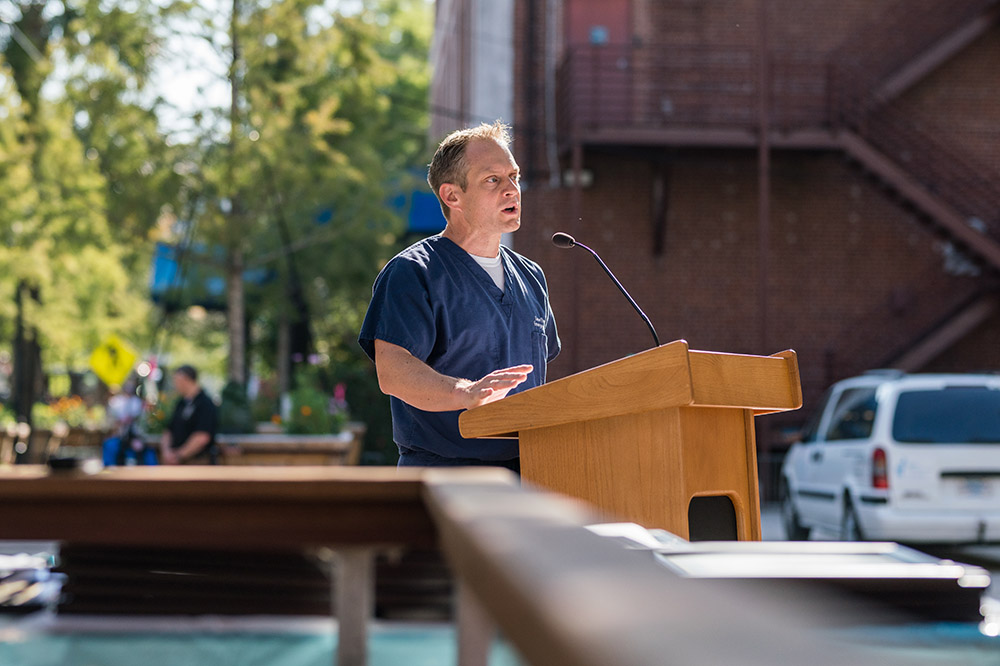 a man speaks at a podium outdoors 