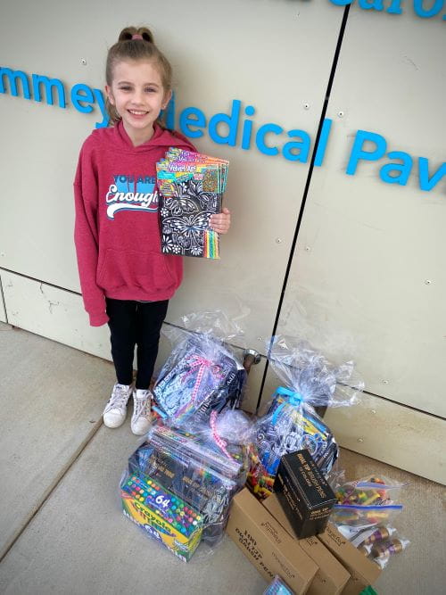 A girl stands in front of the Summey Pavilion with art kits
