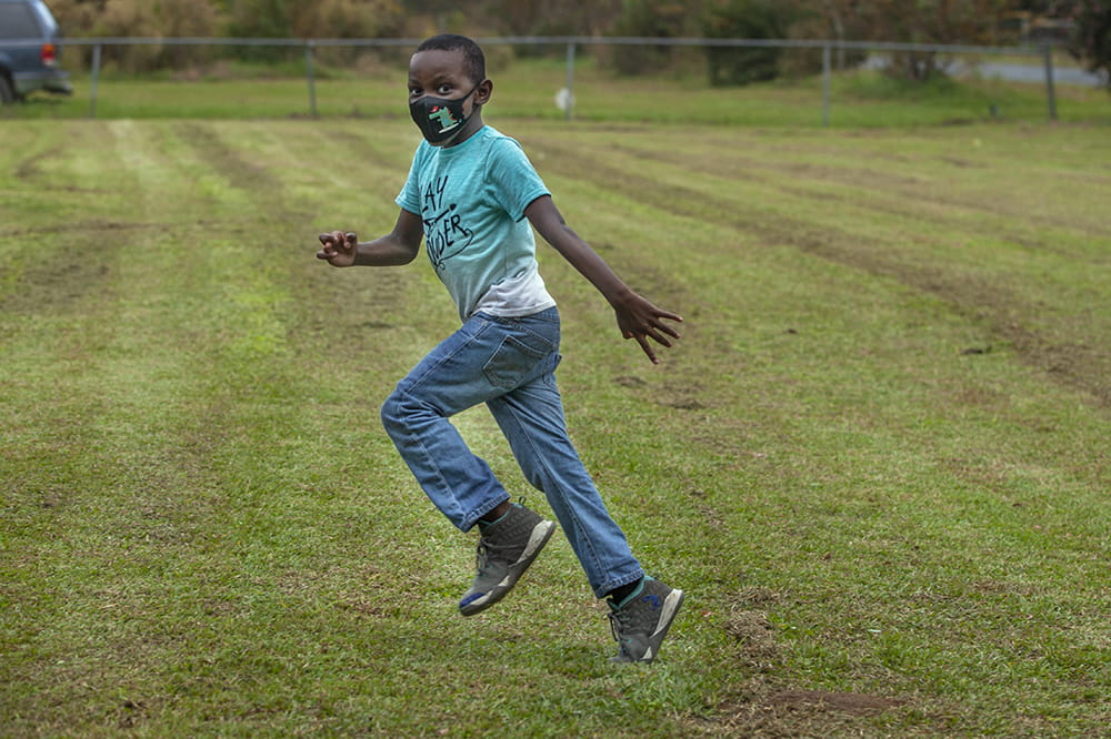 a little boy runs across the grass