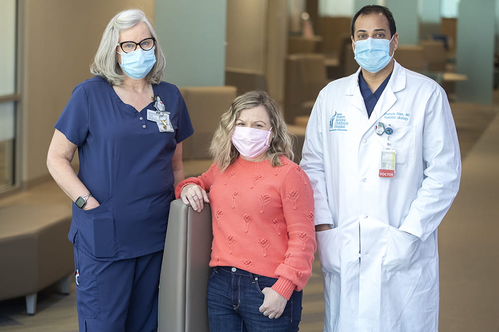A nurse, doctor and patient pose in a lobby area