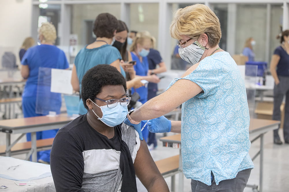 DeAndre White gets COVID vaccine from Charleston County School District nurse Maureen Counasse at Laing Middle School.