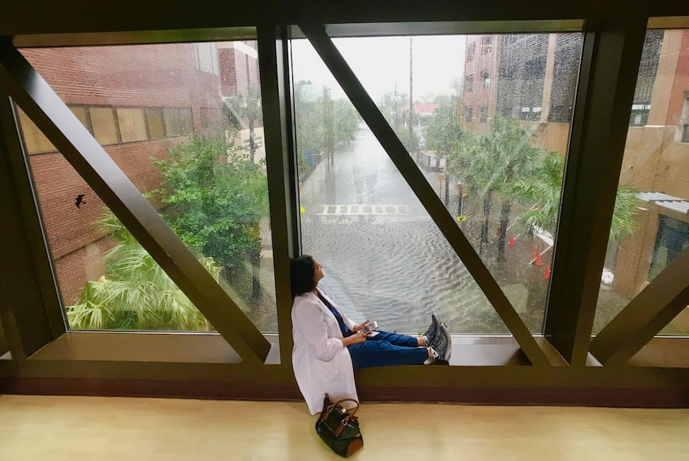 A doctor sits by a window in a crosswalk overlooking flooded streets below