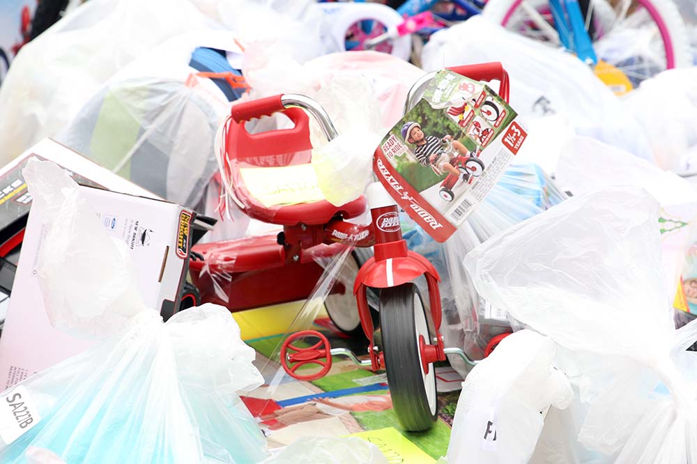 Small red tricycle on a pile of other bagged gifts.