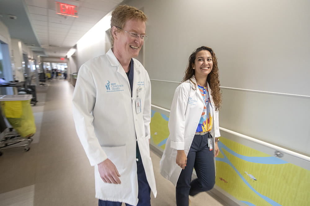 John M. Costello, M.D., M.P.H. Vice Chair of Clinical Research, Department of Pediatrics Director of Research, Children’s Heart Center  MUSC Fellow Stephanie Santana, M.D. Pediatric Cardiology. Man and woman smile while walking.