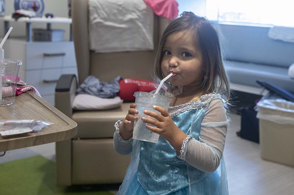 Natalynn Mann sips from a straw while wearing a blue princess costume.
