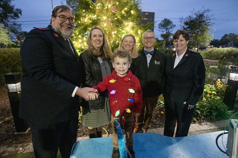 Luke Fossell, 3, is all smiles after lighting the MUSC Christmas tree outside of MUSC Shawn Jenkins Children’s Hospital Monday evening.  Back row: Mike Michels, left, and his wife Cathy Michels, right, captains with the Salvation Army, Amy Hauser, Melissa Kubu and David Zaas, M.D., chief executive officer for the MUSC Health Charleston Division and the chief clinical officer for MUSC Health.  Medical University of South Carolina’s Angel Tree Lighting along with the launch of the Salvation Army’s Angel Tree Program  Patient: Luke Fossell, 3, is waiting for a heart transplant, he got enterovirus at 10 days old and it attacked his heart. 