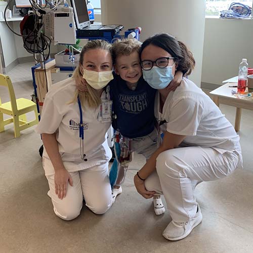 Two nursing students pose with a child in the palliative care area.