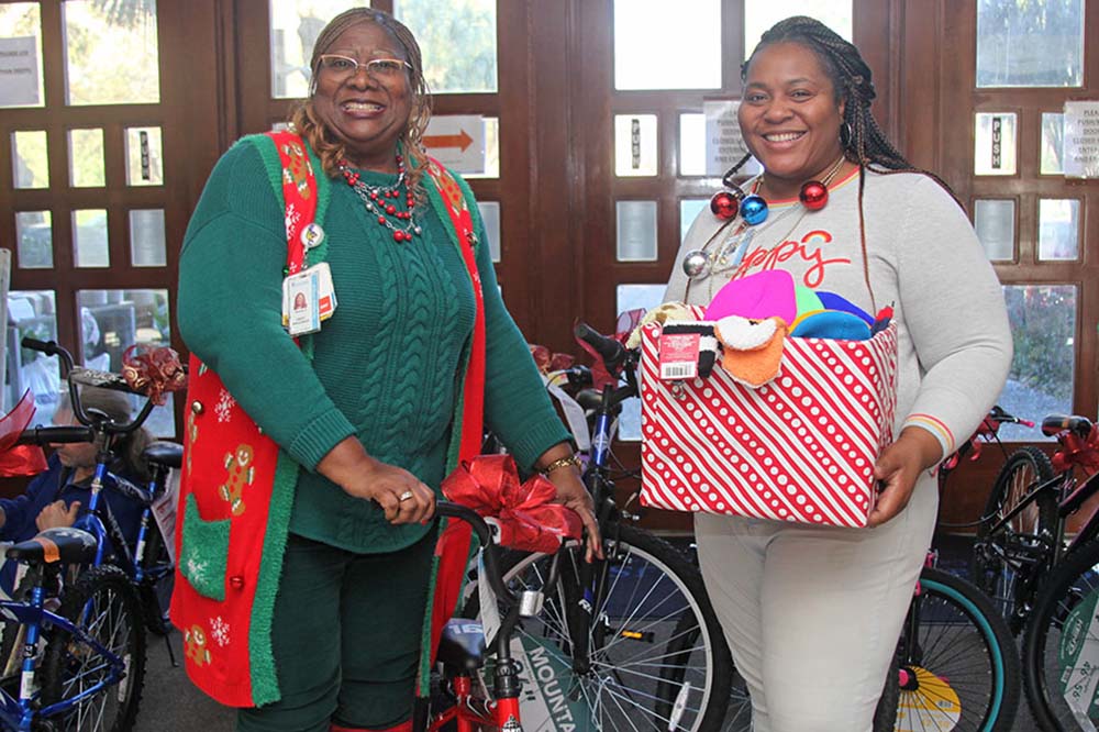Two women smiles while holding gifts for children selected in the Angel Tree program at MUSC.