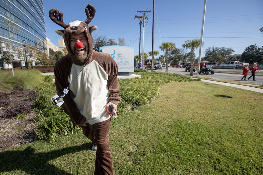 Man wearing a reindeer costume laughs during parade