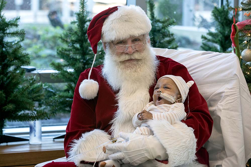 Santa holds a yawning baby.