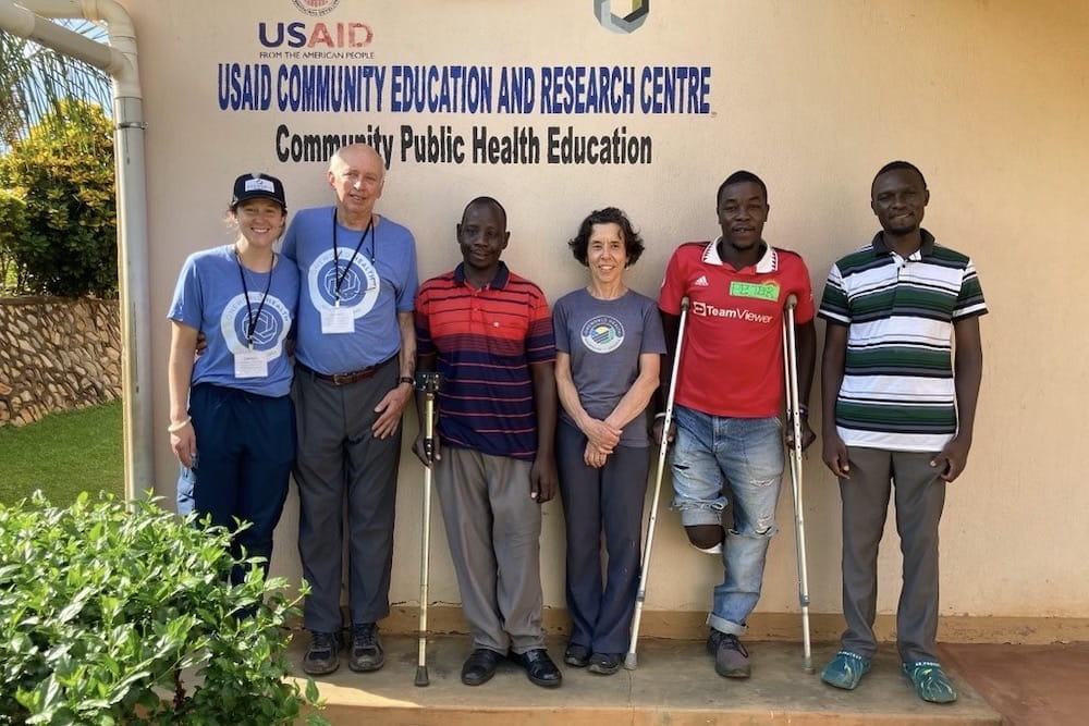 A group of six people stand in front of a clinic in Uganda
