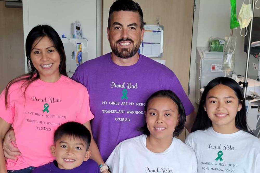 Two adults in pink and purple shirts stand behind three children. Ava, bottom center, received a bone marrow transplant from her sister Alyssa (right).