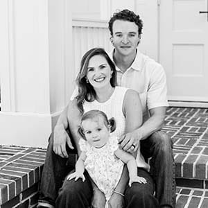 Little girl with pigtails with a woman and a man who are holding each other.