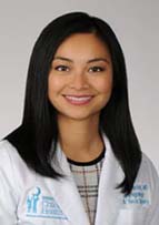 Smiling woman with long dark hear wearing a white doctor's coat